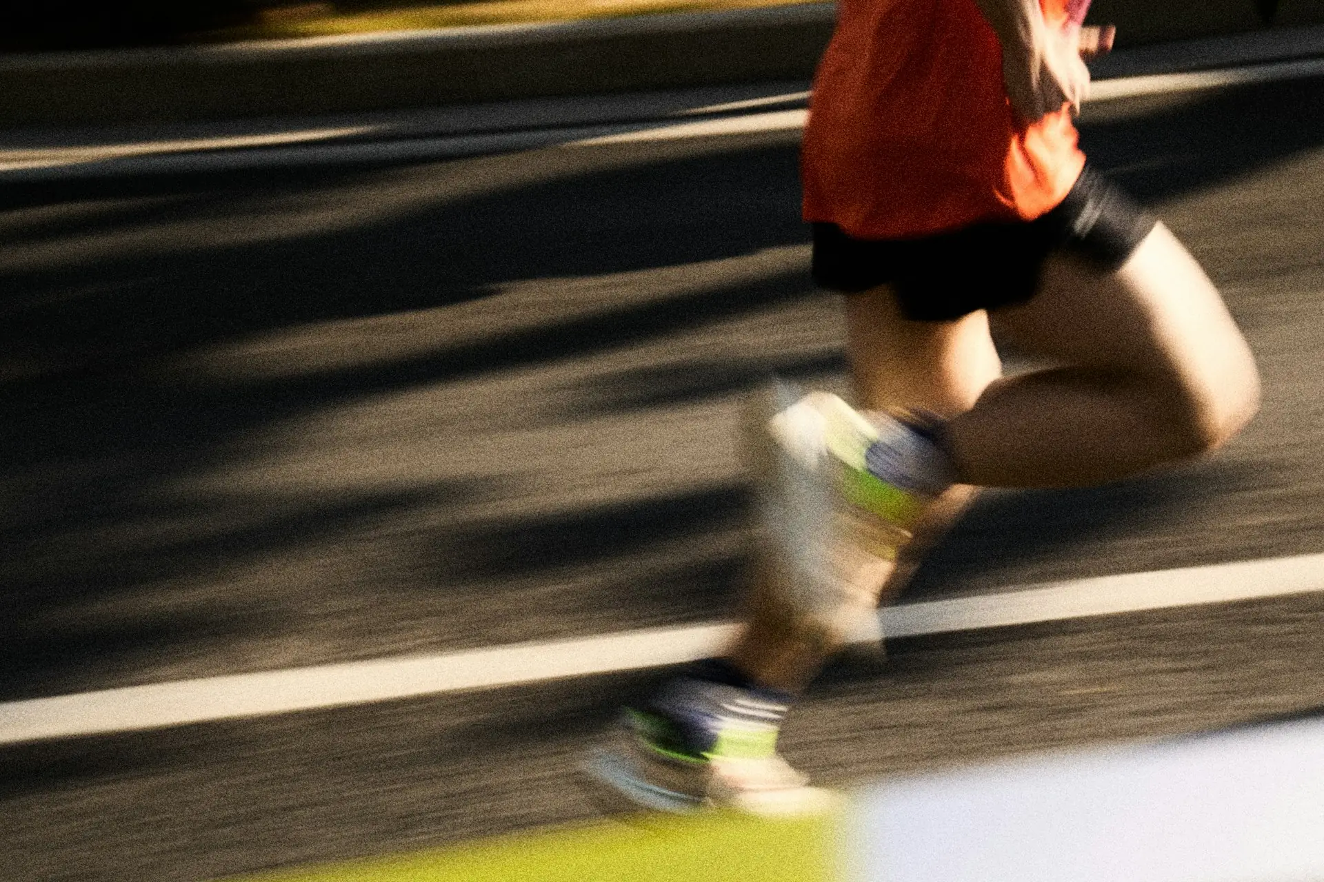 Runner in a red top running along a road